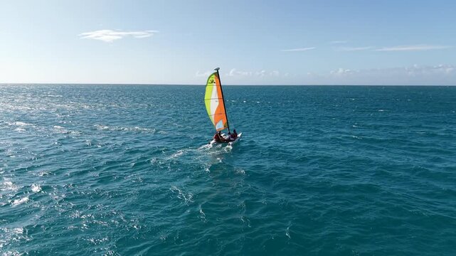 Aerial drone footage of sailing boat excursion with people enjoying Caribbean ocean adventure in the Dominican Republic surrounded by vivid blue tropical water.