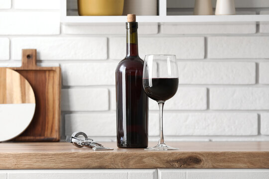 Bottle with glass of red wine and opener on counter in kitchen