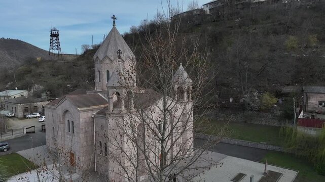 Aerial view of Saint Gregory of Narek Church in Kapan, showcasing its beautiful traditional tuff stone architecture, distinct domes, and scenic mountain landscape in the surrounding background