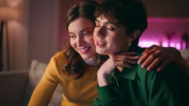 Videocalling lesbian couple talking sharing news sitting night apartment closeup
