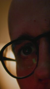 Portrait close up: man working at night looking at monitor, reflections in eyeglasses. Person stock market trader using laptop at office or home office. Business distance work, freelancer male