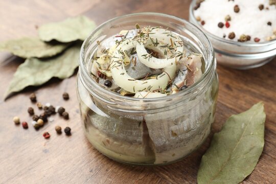 Marinated herring with spices on wooden table, closeup