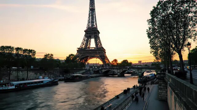 Elevated video of majestic Eiffel Tower silhouetted against vibrant golden-pink Parisian sunset over shimmering River Seine, historic bridge, silhouetted people. Romantic Paris concept.