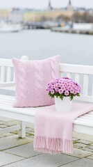 Obraz premium Pink cushion and flowers arranged on bench by waterfront