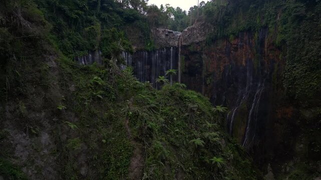 Cinematic aerial view of Tumpak Sewu Waterfall in East Java &ndash; Breathtaking drone shot of massive tropical canyon in warm sunrise light and morning mist, premium Indonesia landscape 4k footage