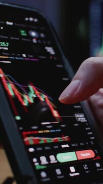 Terminal app. Close up of trader man hand holding smartphone, using trading application with stock market charts for financial analysis and monitoring investment data. Bitcoin or USD currency