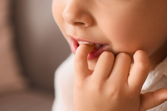 Little girl biting nails at home, closeup
