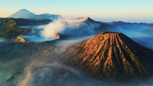 Cinematic aerial view of Mount Bromo volcano at sunrise &ndash; Breathtaking drone shot of morning mist covering the vast caldera and dramatic mountain peaks in East Java, Indonesia landscape 4k