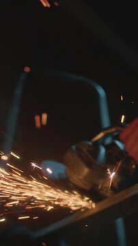 Male industrial or construction worker cuts metal with a angle grinder. Man uses circular saw at garage or workplace. Cutting raw material with flying red sparks at the factory or plant. Slow motion