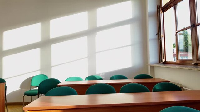 Morning sun light streams into an empty classroom. Perfect back to school 4K stock footage of sunlight on school desks b-roll