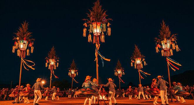 Traditional Balinese Penjor decorations illuminated at night during a festival.