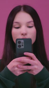 Portrait: young brunette woman with black hair, typing text on phone, schoolgirl. Closeup: young white kid using smartphone, texting. Teen girl use app social media. Teenager wear pullover in studio