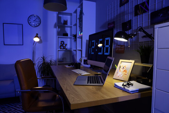 Programmer's desk with computer and laptop in office at night