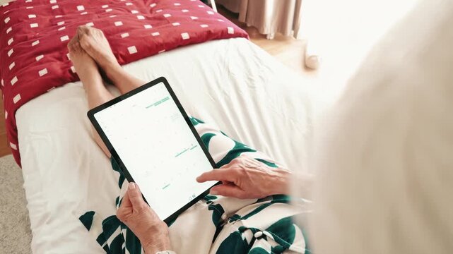 Senior Woman Browsing Tablet While Resting in Bed 
