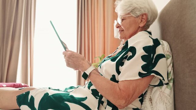 Senior Woman Browsing Tablet While Resting in Bed 