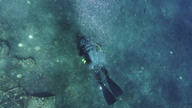 Scuba diver swimming over a rocky seabed