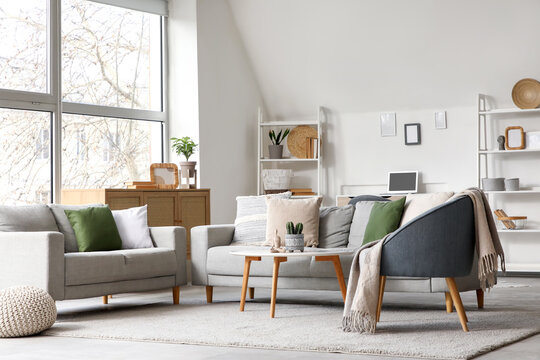 Stylish interior of living room with grey sofas and armchair