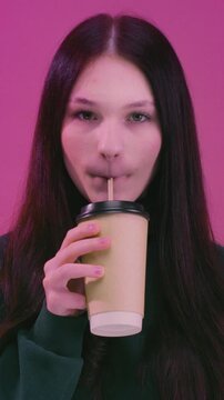 Teen brunette girl enjoying hot tea. Young woman holding take away coffee paper cup, cardboard. Female drink warm beverage outdoors, casual lifestyle moment, cozy mood, urban background, close-up shot