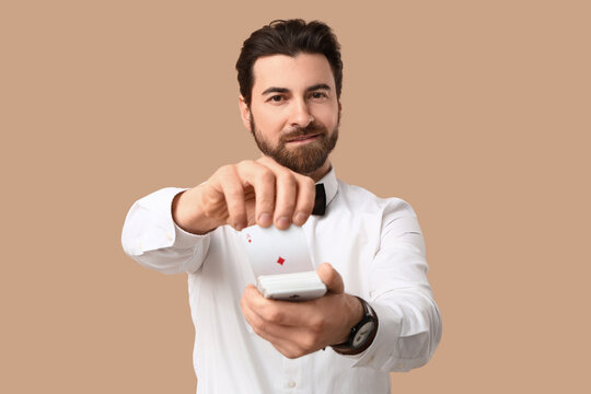 Handsome male banker with playing cards for poker on beige background