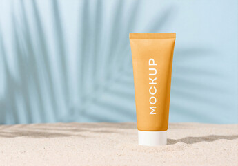 Yellow cosmetic cream tube mockup standing on a sandy beach with tropical palm leaf shadow on a light blue background