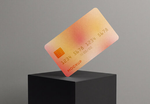 Floating credit card mockup with orange gradient design balancing on a black cube podium isolated on a gray background