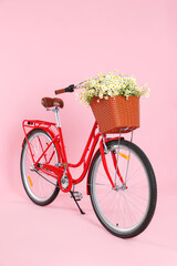 Fototapeta na wymiar Bicycle with basket of beautiful wildflowers on pink background