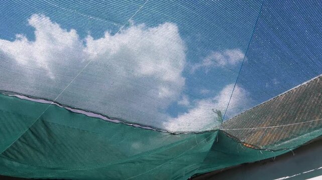 Green sunshade netting blowing in wind