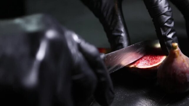 Chef con guantes negros cortando un higo maduro. Chef profesional con guantes negros cortando un higo maduro. Preparaci&oacute;n culinaria artesanal, ingrediente gourmet de temporada.