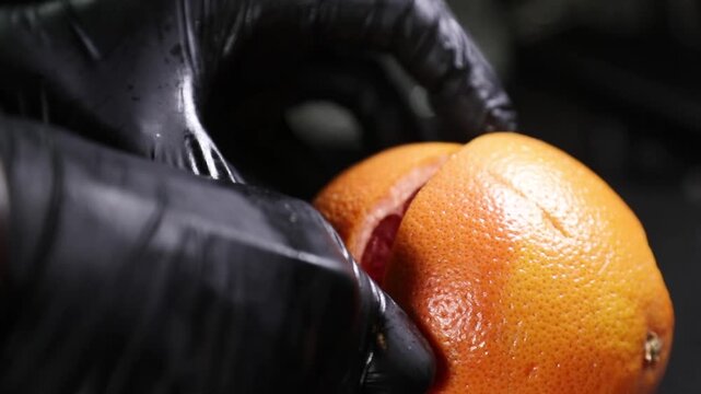 Chef cortando una naranja fresca con un cuchillo sobre una encimera negra. Chef profesional cortando una naranja fresca con un cuchillo. Preparaci&oacute;n culinaria artesanal, ingrediente c&iacute;trico gourmet.
