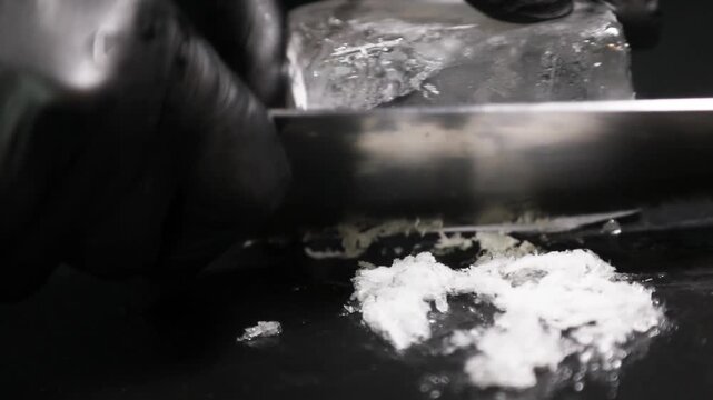 Barman cortando un bloque de hielo para un c&oacute;ctel sobre fondo negro. Barman profesional tallando hielo para un c&oacute;ctel sobre fondo negro. Bar artesanal, t&eacute;cnica de hielo artesanal.