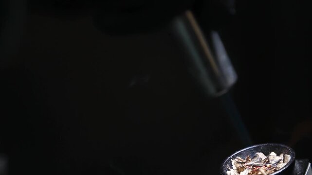 Barman encendiendo ahumador de c&oacute;cteles con soplete sobre fondo negro. Barman profesional encendiendo ahumador de madera con soplete. C&oacute;ctel ahumado, t&eacute;cnica de bar vanguardista y teatral.