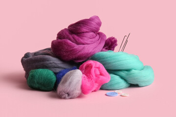 Heap of different wool for felting, needles and buttons on pink background © Pixel-Shot