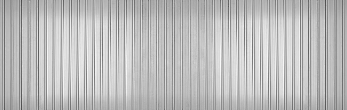 Abstract seamless industrial corrugated silver metal sheet texture with a gray and white striped pattern backdrop