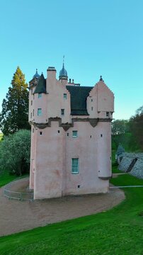 Craigievar Castle appears in a cinematic video where the camera starts in a close view of its pink stone details and gradually pulls back to reveal the full castle surrounded by forest and rolling Sco