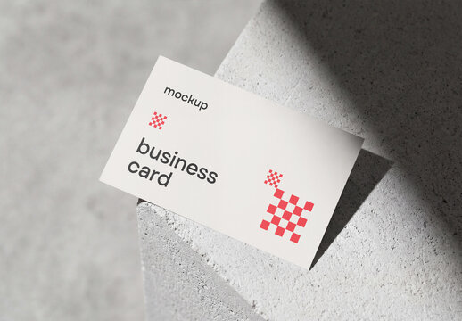 Minimal business card mockup lying on a concrete stone block with dramatic harsh shadow background