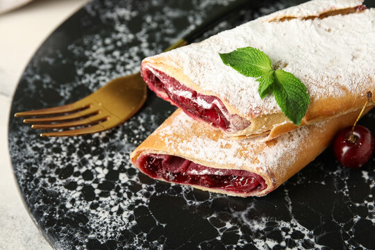 Plate with tasty cherry strudel on light background, closeup