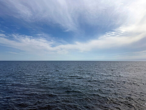 Open sea with calm blue water and sky clouds.