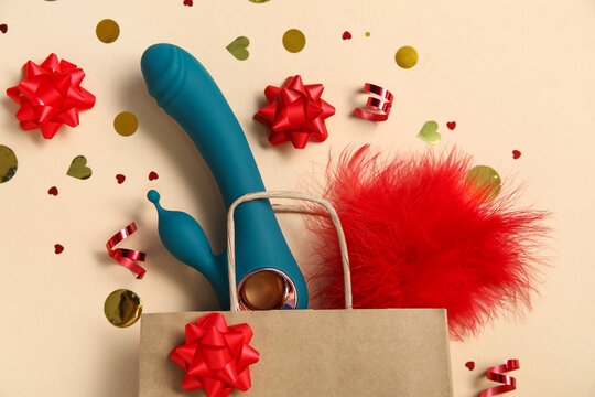 Composition with shopping bag, sex toys, gift bows and confetti on color background