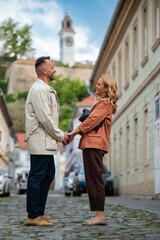 Obraz premium Smiling couple holding hands exploring novi sad street