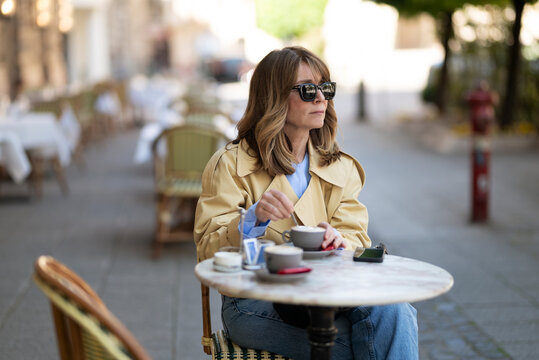 Sophisticated mature woman enjoying morning coffee at a european sidewalk cafe