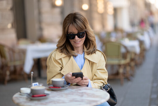 Sophisticated mature woman enjoying morning coffee at a european sidewalk cafe