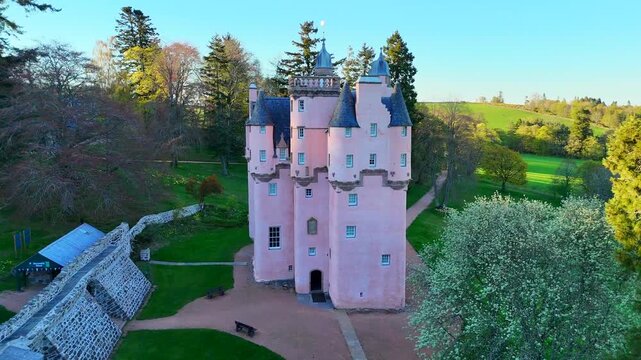 Craigievar Castle appears in a cinematic video as the camera slowly reveals the castle through drifting mist, with gentle movement across its pink towers and surrounding forest under soft Scottish lig