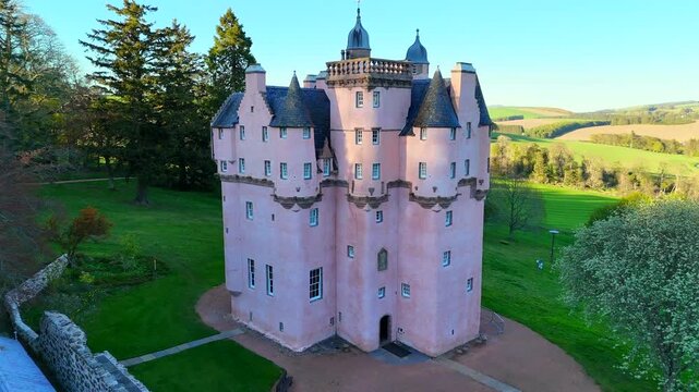 Craigievar Castle appears in a cinematic video where the camera slowly zooms in from a wide aerial view, drawing closer to its pink towers as details of the stonework and windows become increasingly v