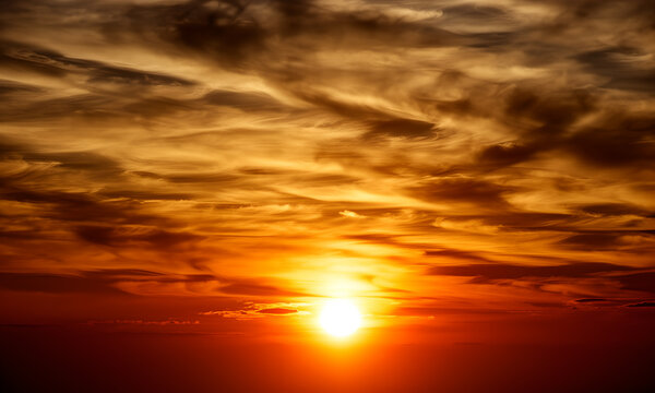 Vibrant orange and red sunset sky with bright sun and dramatic fiery clouds
