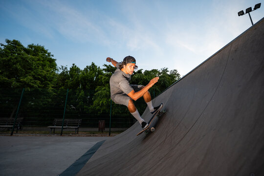 Skateboarder riding halfpipe in skatepark during evening