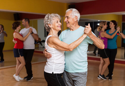 Senior couple dancing salsa in colorful class for adults