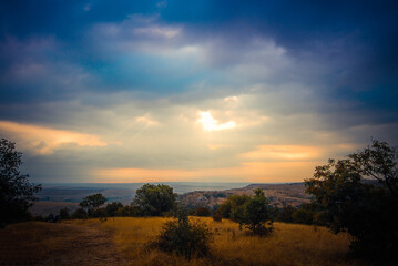 Fototapeta premium Serene landscape with dramatic clouds over a vast golden field at sunset.