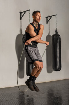 young Hispanic boxer jumping crossed rope during gym training