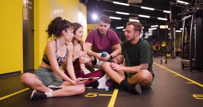 Fitness group meets at center for exercise session with friends discussing workout plans and sharing tips for healthy living