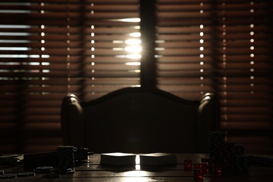 Mafia. Playing cards, casino chips and dice on wooden table in dark room